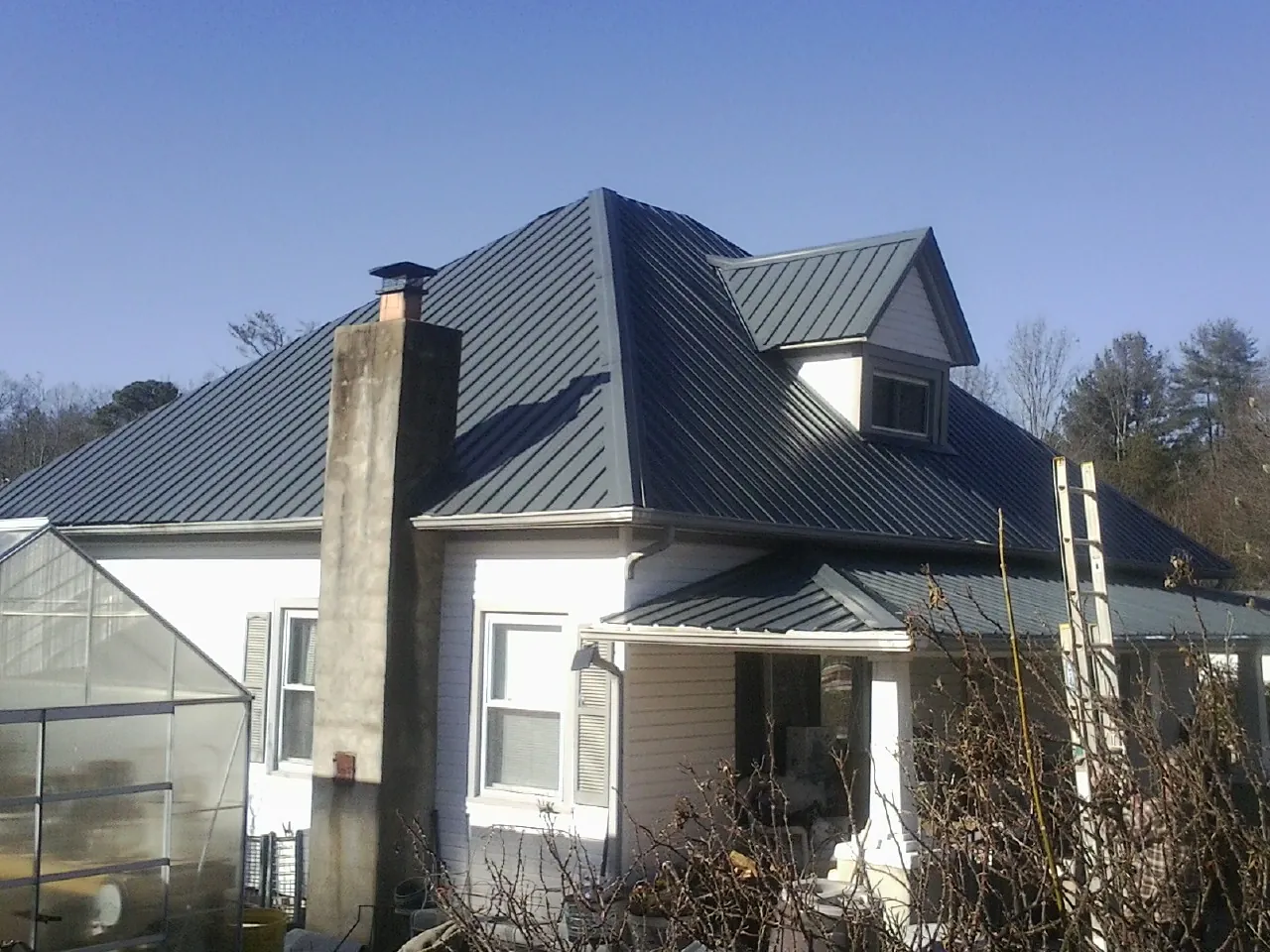 Dark blue standing seam metal roof on a white farmhouse with dormer — Slate & Tile Roof Repair by Roofing Brothers in Lovejoy